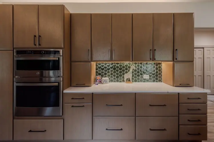 Modern Vero Beach kitchen with custom wood cabinets, double wall ovens, and green hex tile backsplash