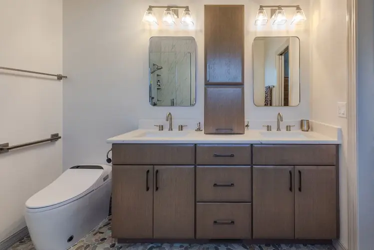Modern dual-sink bathroom vanity with central storage tower and sleek lighting fixtures